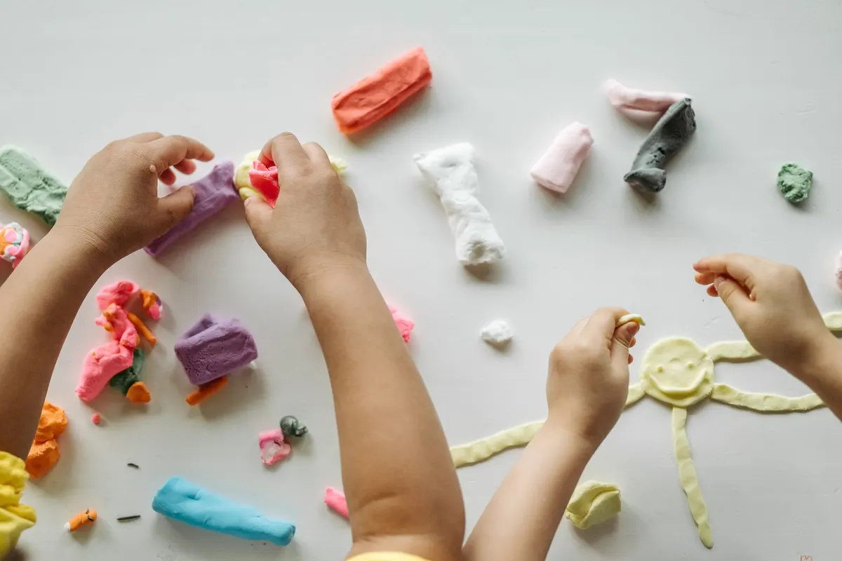 Enfants qui façonnent des formes en pâte à modeler colorée sur une table claire