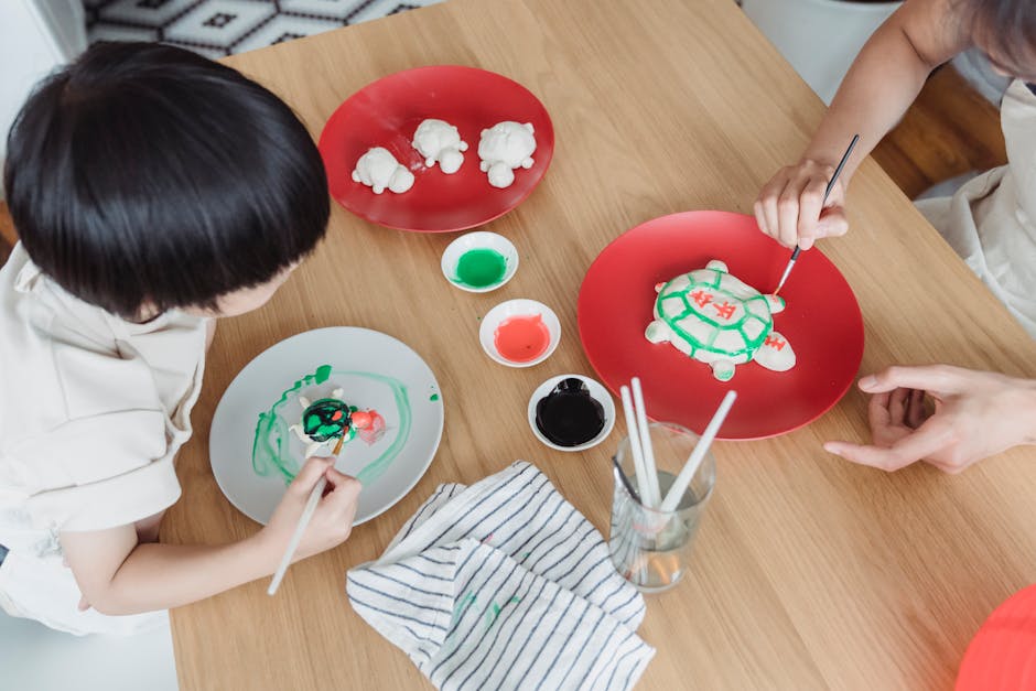 Gros plan sur les mains d'un enfant appliquant de la peinture colorée sur une statuette en plâtre