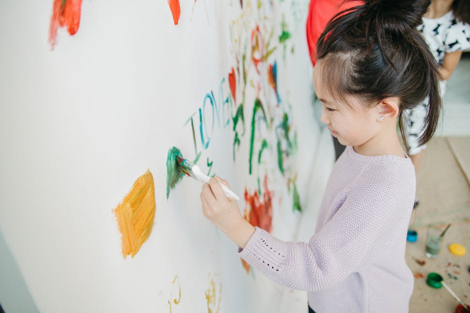 Enfant appliquant délicatement de la gouache au pinceau fin sur les reliefs d'un moulage en plâtre