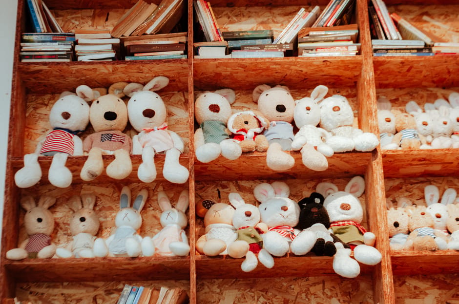 Collection de statuettes et figurines en plâtre peintes par des enfants, exposées sur une étagère en bois